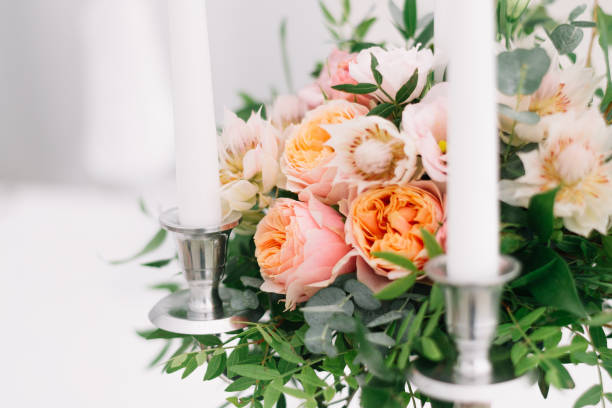 istock Beautiful wedding floral decoration on a table in a restaurant. White tablecloths, bright room, candles, close-up shooting. The event, happiness, honeymooners. Soft bokeh white background 865015362