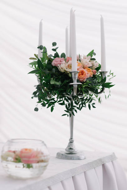 istock Beautiful wedding floral decoration on a table in a restaurant. White tablecloths, bright room, candles, close-up shooting. The event, happiness, honeymooners. Soft bokeh white background 865015456