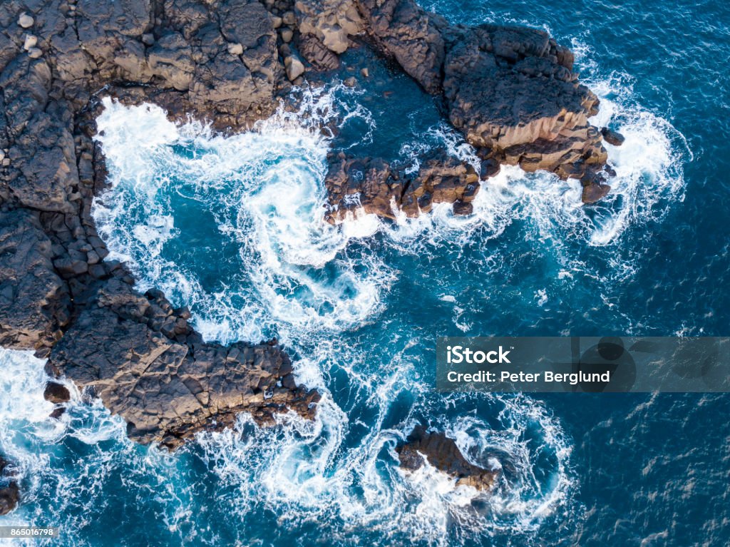 Waves splashing against volcanic rocks Waves swirling and splashing against rocks from an aerial view. Rock - Object Stock Photo