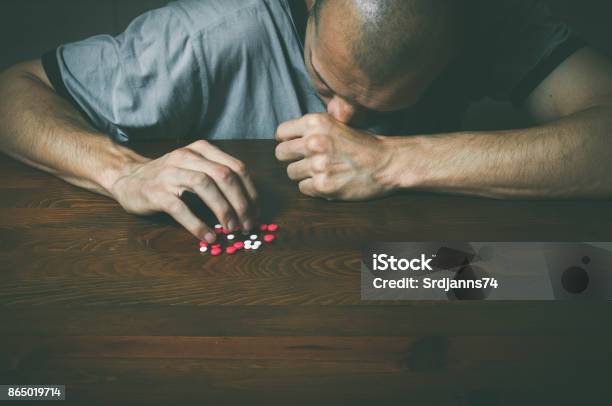 Depressed Man Suffering From Suicidal Depression Want To Commit Suicide By Taking Strong Medicament Drugs And Pills Stock Photo - Download Image Now