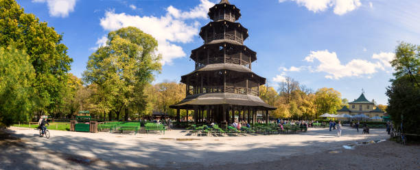 imagen panorámica de la torre de china con el jardín de la cerveza en el jardín inglés en munich en un bonito día de otoño. personas sentadas en el jardín de la cerveza. - englischer garten fotografías e imágenes de stock