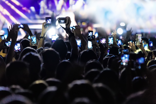 Hand with a smartphone records live music festival, Taking photo of concert stage, live concert, music festival, happy youth, luxury party, landscape exterior