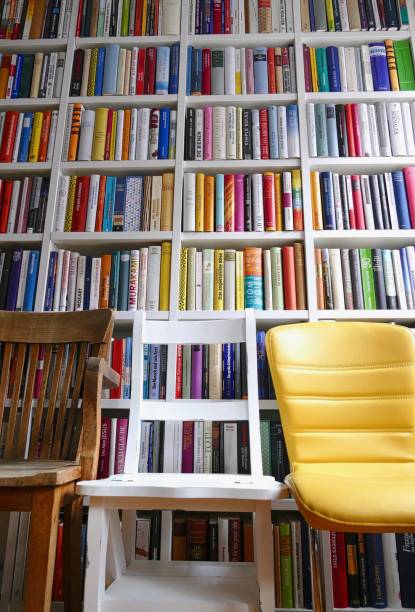 istock Take a seat: Three chairs in front of a colorful library books shelves 865036326