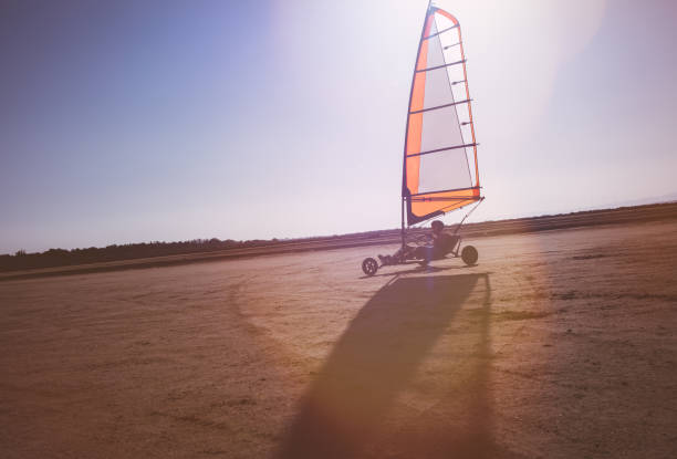 Young man doing land sailing on the beach in summer Young man on island vacations doing land sailing on the beach in summer kite sailing stock pictures, royalty-free photos & images