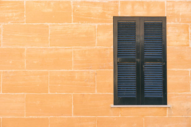 Close up image of a sandstone wall contrasting against bright blue wooden shutters