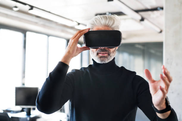 Mature businessman with VD goggles in the office. Handsome mature businessman with virtual reality goggles in the office. virtual reality point of view photos stock pictures, royalty-free photos & images