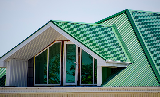 La casa con ventanas de plástico y un techo verde de la hoja acanalada. Techo verde de perfil metálico acanalado y ventanas de plástico. photo