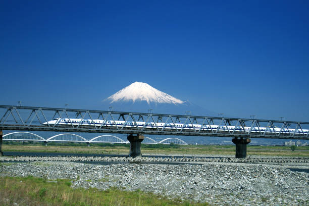 Travel fast and comfortable A bullet train (japanese shinkansen) running with top speed at the foot of the Fuji-san. bullet train mount fuji stock pictures, royalty-free photos & images