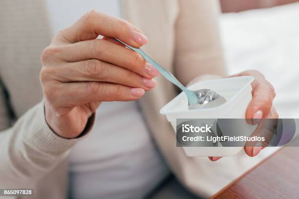 Senior Woman Eating Yogurt Stock Photo - Download Image Now - Yogurt, Eating, Senior Adult