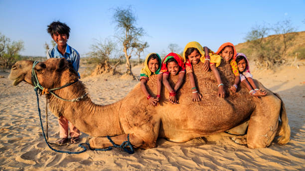 Group of happy Gypsy Indian children with camel, desert village, India Group of happy Gypsy Indian children having fun with camel - desert village, Thar Desert, Rajasthan, India. thar desert stock pictures, royalty-free photos & images
