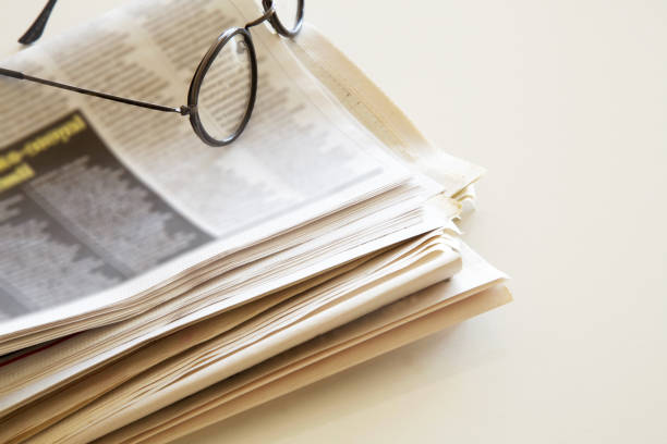istock Newspaper with eyeglasses on brown background 865149294