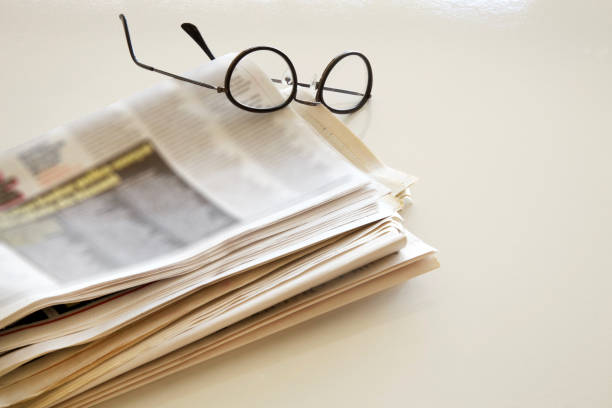 istock Newspaper with eyeglasses on brown background 865149468
