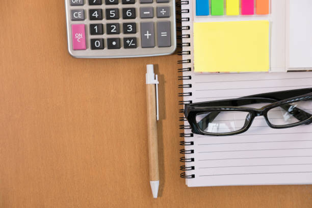 istock sticky note, calculator, ballpoint pen, empty notebook, eyeglasses on office desk. business, accountant concept. Top view with copy space. selective focus. 865154296