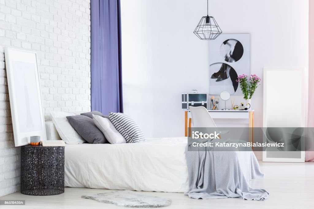 Designer table in woman's bedroom Designer table next to bed in woman's bedroom with flowers and cosmetics on dressing table Adult Stock Photo