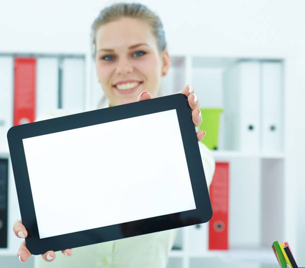 istock Young smiling woman showing blank tablet computer screen in office. Focus on tablet computer. 865154660
