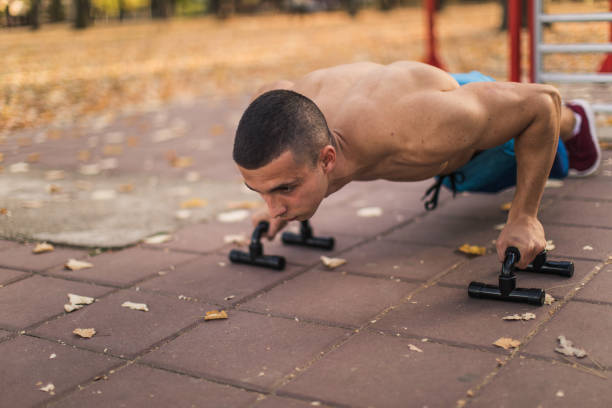 Push-ups outdoors Young man workout on exercise machine outdoors. Calisthenics training concept gymnastics bar photos stock pictures, royalty-free photos & images