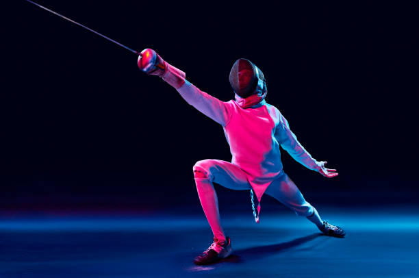 male fencer in action male fencer attacking with a sword isolated on black background fencing sport stock pictures, royalty-free photos & images