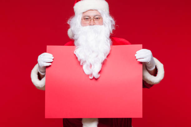 istock Santa Claus pointing in blank advertisement banner isolated on red background with copy space red leaf 865192990