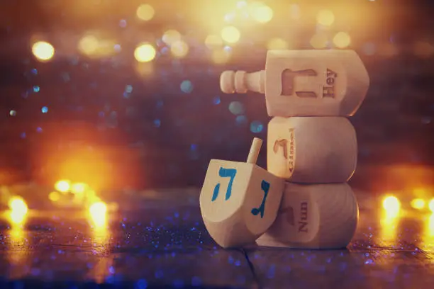 Image of jewish holiday Hanukkah with wooden dreidels colection (spinning top) and glowing gold lights on the table