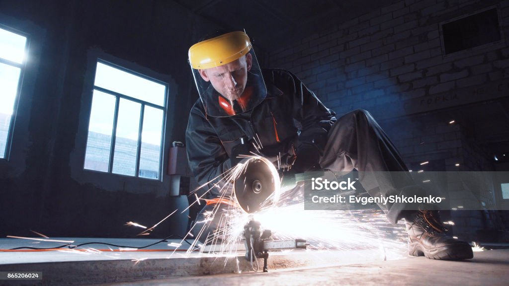 Man cutting metal using grinding machine Man wearing protective mask cutting metal with grinder in hangar Grinder - Industrial Equipment Stock Photo