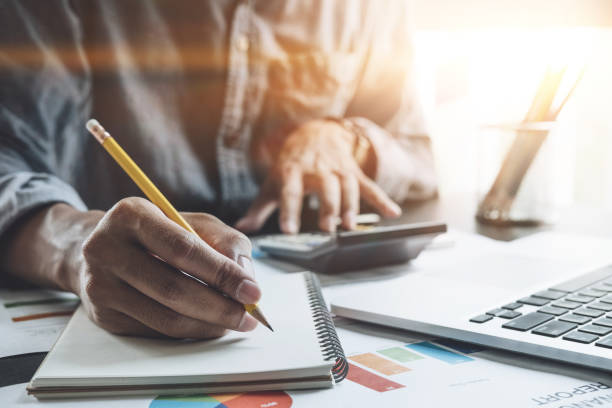 istock Businessman with calculator and laptop computer counting with cost and writing make notes at office, Business financial concept 865226676
