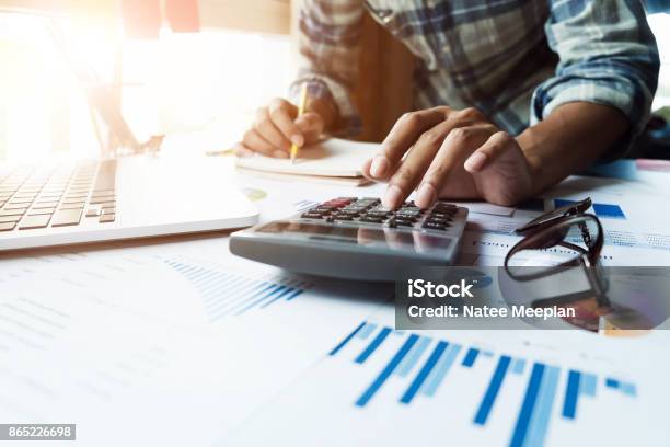 Close Up Of Businessman Or Accountant Hand Holding Pen Working On Calculator And Laptop Computer To Calculate Business Data During Make Note At Notepad Accountancy Document At Office Business Financial Concept Stock Photo - Download Image Now