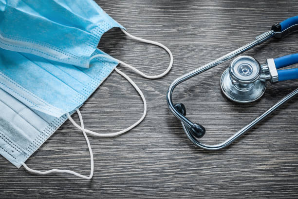 istock Disposable protective face masks stethoscope on wooden board 865268020