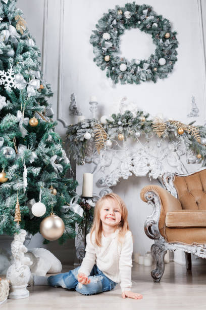 クリスマス ツリーの近くに床の上に座って、おもちゃを探してブルー ジーンズで愛らしい小さなブロンドの女の子。 - gift little boys people blond hair ストックフォトと画像
