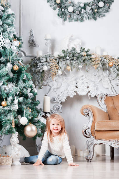 クリスマス ツリーの近くに床の上に座って、おもちゃを探してブルー ジーンズで愛らしい小さなブロンドの女の子。 - gift little boys people blond hair ストックフォトと画像