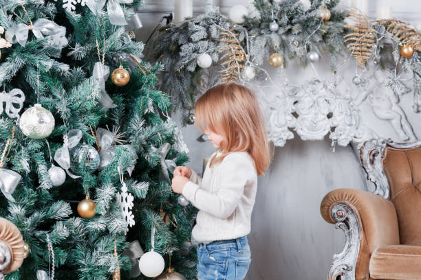 クリスマス ツリーの近くに床の上に座って、おもちゃを探してブルー ジーンズで愛らしい小さなブロンドの女の子。 - gift little boys people blond hair ストックフォトと画像