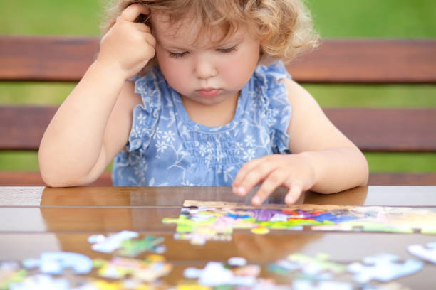 difficult task. tired child playing jigsaw with serious face. - jigsaw puzzle solution one person people imagens e fotografias de stock