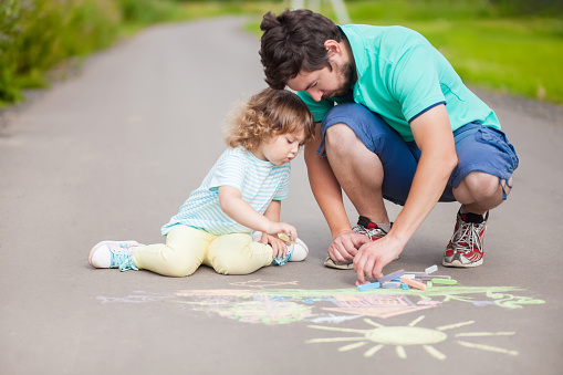 Caring father, happy family. Drawing with color chalk. Happy childhood. Preschooler leisure time. Kids spending time with parents. Artistic talented kids. Father and daughter relationshionships.