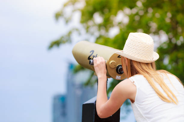 istock Woman tourist with sun hat looking through telescope 865317636