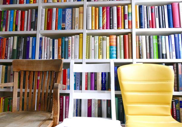 istock Take a seat: three chairs in front of a colorful library books shelves 865317746