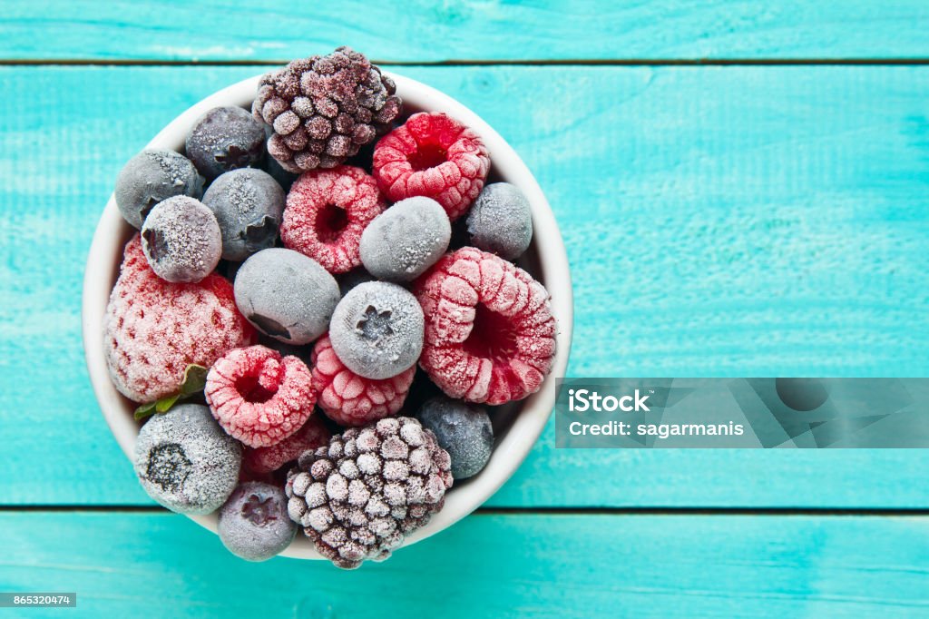 Various frozen berries on a bowl placed against blue background Frozen berries bowl on blue background Frozen Stock Photo