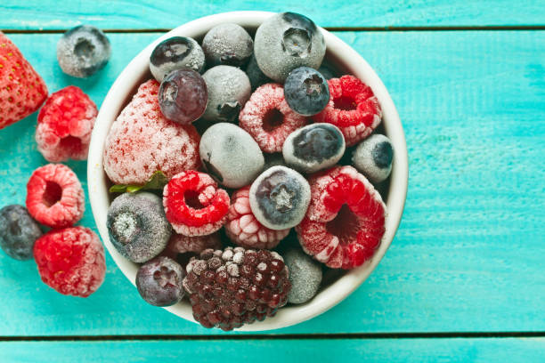 istock Mix frozen berries in a bowl against blue background 865324468