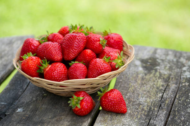 Basket with strawberries on a garden wooden table