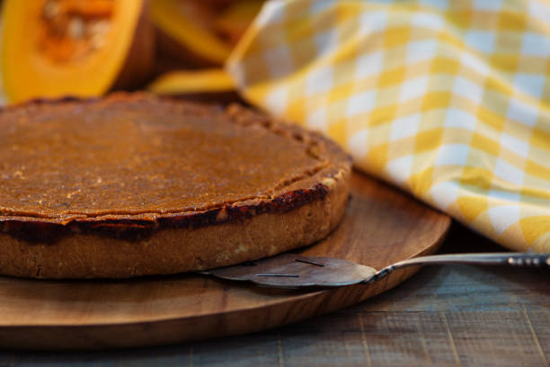 istock pumpkin pie with cinnamon  and fresh pimpkin with napkin on rustic wooden background 865327946