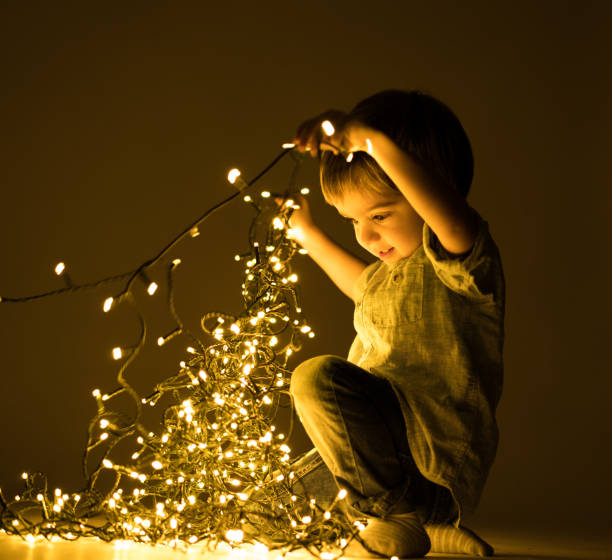 happy three years old boy with christmas lights decoration