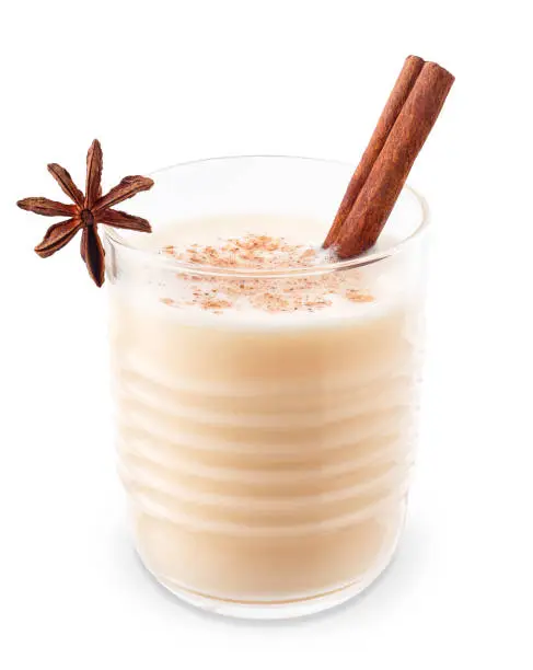 eggnog in glass with anise star and cinnamon stick isolated on white background with clipping path. Christmas drink. Alcohol sweet cocktail. Traditional festive winter beverage