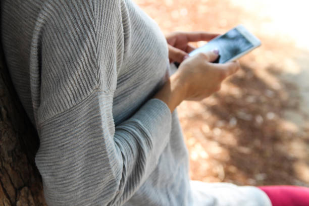 una donna che tiene un telefono nel parco - hiding internet multimedia people foto e immagini stock