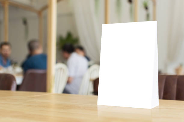 istock Mock up blank template menu frame on wood table in restaurant with blurred background, Clipping path included 865342596