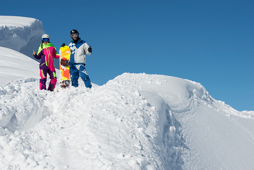 Young couple standing at deep snow on mountain peak.