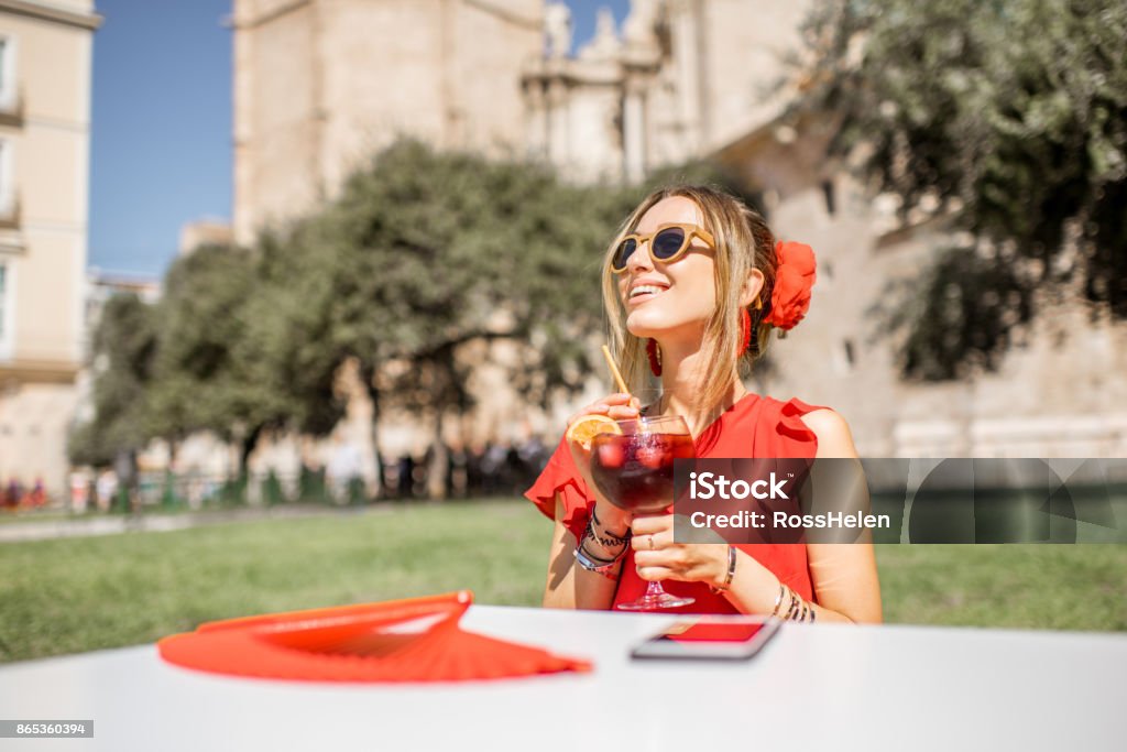 Woman with sangria drink outdoors in Valencia Young woman in red enjoying sangria, traditional spanish alcohol drink, sitting outdoors in the center of Valencia old town Sangria Stock Photo