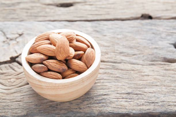 istock group of almonds  from wood bowl on wood background 865360714