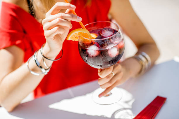 Woman with glass of Sangria drink Woman holding a glass with Sangria, traditional spanish alcohol beverage made of wine, sitting outdoors at the restaurant. Image with no face focused on the glass sangria stock pictures, royalty-free photos & images