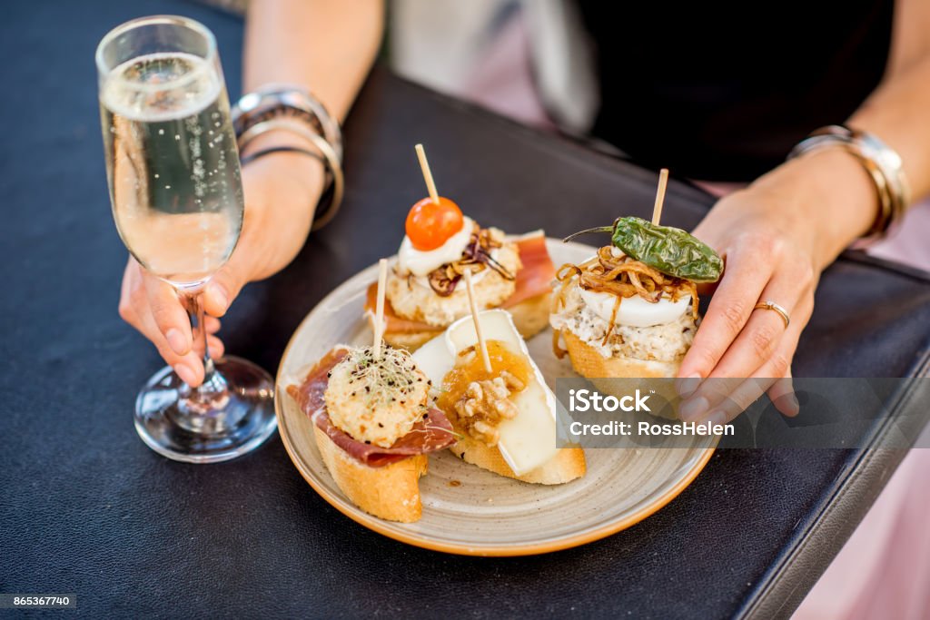 Set of pinchos on the table Beautiful and colorful set of pinchos, traditional spanish snack related to tapas, with glass of wine outdoors on the table Tapas Stock Photo