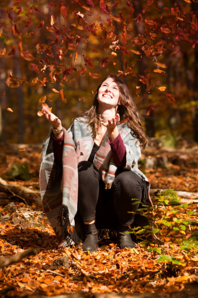 istock young woman throwing leaves in the air 865367854