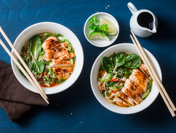 sopa de fideos de udon picante estilo asiático con pollo frito sobre fondo azul, vista superior - bok choy fotografías e imágenes de stock