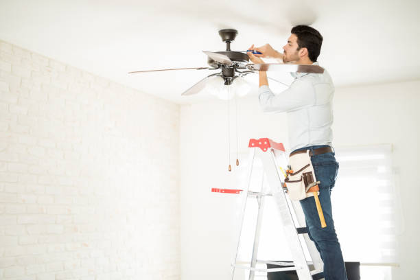 Electrician fixing a ceiling fan Profile view of a male electrician stepping on a ladder and installing a ceiling fan in a house ceiling fan stock pictures, royalty-free photos & images